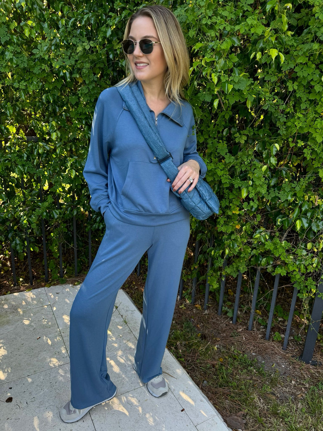 BK Caroline Half Zip-Up Collar Sweatshirt in Gray Blue paired with matching Cindy High-Waist Wide Leg Sweatpants, Le Specs Neptune Deux Sunnies, Vee Collective Porter Messenger Bag in Denim - all available at Barbara Katz