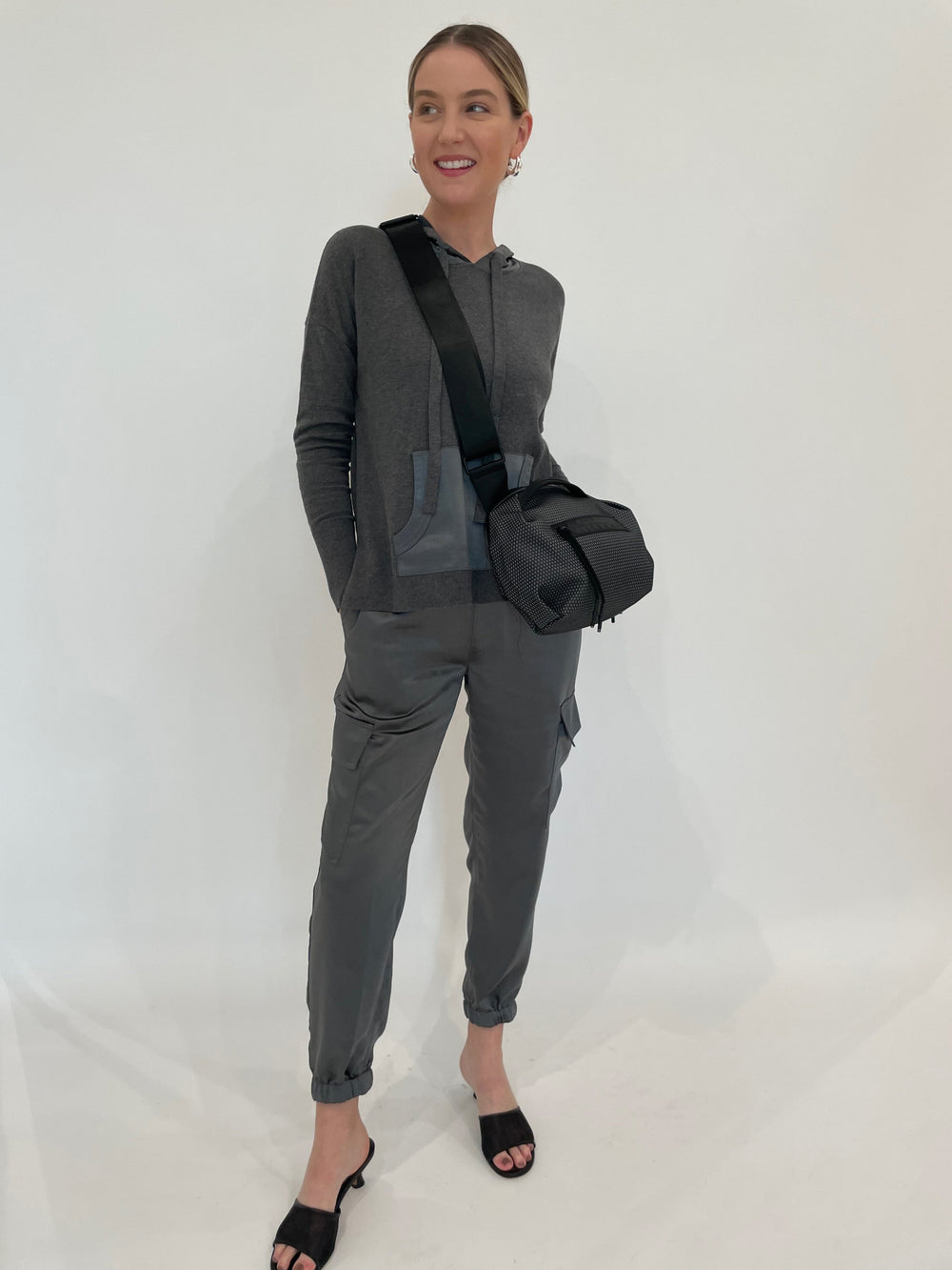 J Society Juno Satin Cargo Pants in Gunmetal paired with matching J Society Roxie Satin Pocket Hoodie in Gunmetal, Lizzie Fortunato Onda Hoops in Silver, Daniella Lehavi Bonnie Crossbody Bag in Grey available at Barbara Katz