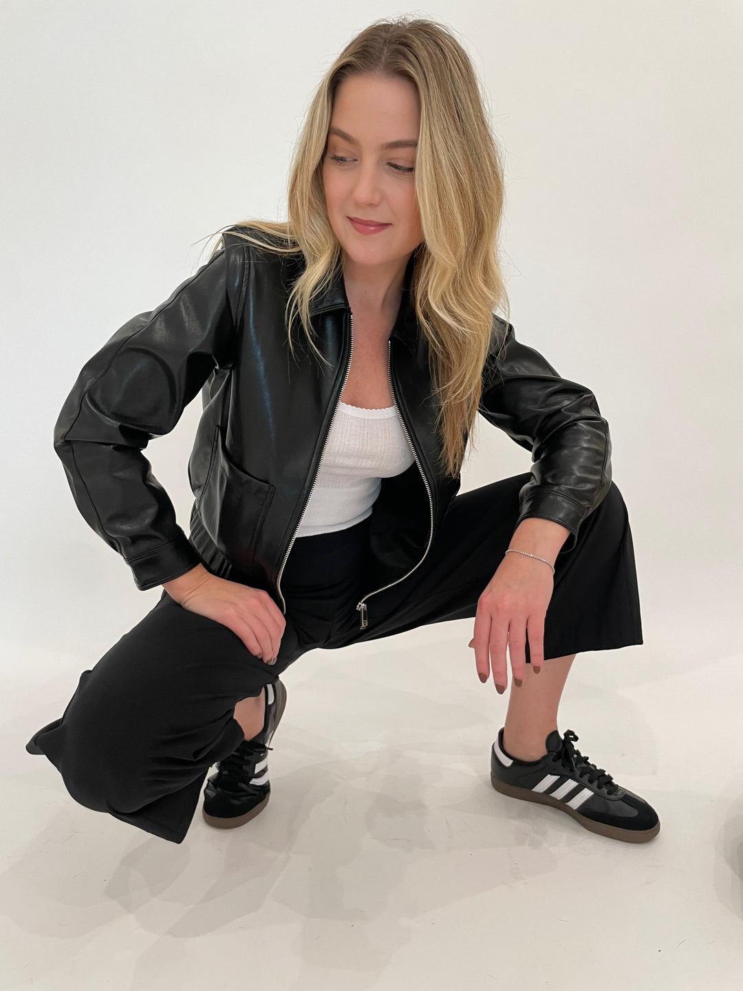 Melisssa Nepton Dona Faux Leather Bomber Jacket in Black with Goldie White Pointelle Camisole underneath, paired with Raffaello Rossi Sally 7/8 High Tech Jersey Pants in Black - all available a Barbara Katz