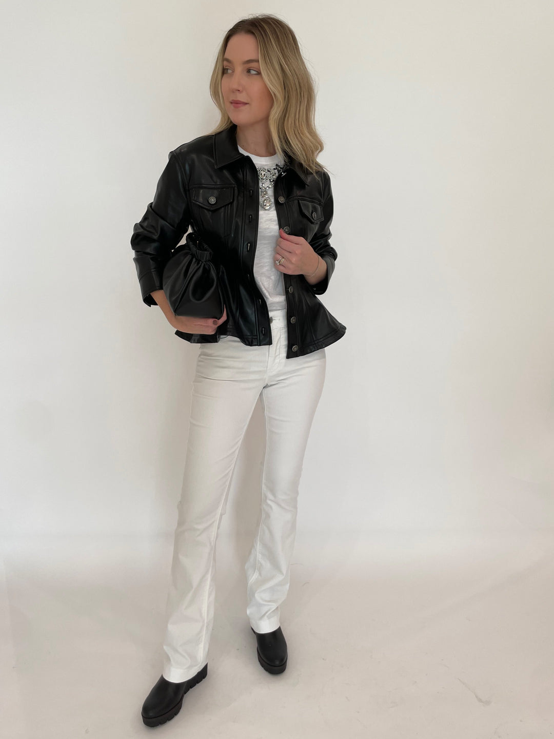 Cinq a Sept Applique Jewelry Tee in White paired with MAC Dream Wide Wonderlight Jeans 32" in White Denim, Cinq a Sept Gina Vegan Leather Jacket in Black, DeMellier Miami Clutch in Black, Gabor Black Leather Boots - all available at Barbara Katz