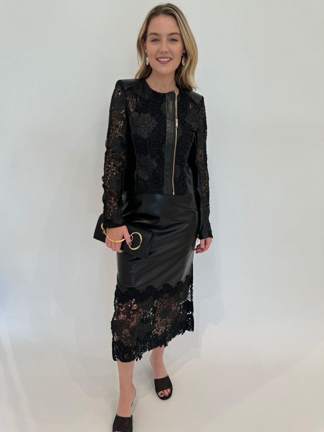 Generation Love Dalma Vegan Leather Guipure Jacket in Black paired with Chantira Vegan Leather Guipure Skirt, Lizzie Fortunato Taj Disc Earrings in Mother-of-Pearl, Alexis Bittar Twisted Gold Side Handle Clutch Bag in Black available at Barbara Katz