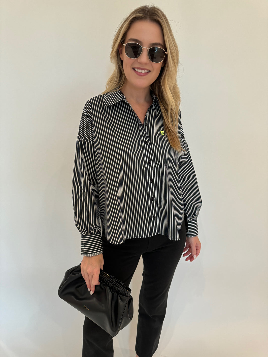 Essentiel Antwerp Glee Striped Cotton Shirt in Black Combo paired with Lysse Ankle Denim Bootcut Pants in Black, Le Specs Neptune Deux Sunglasses and DeMellier Miami Clutch in Black - all available at Barbara Katz