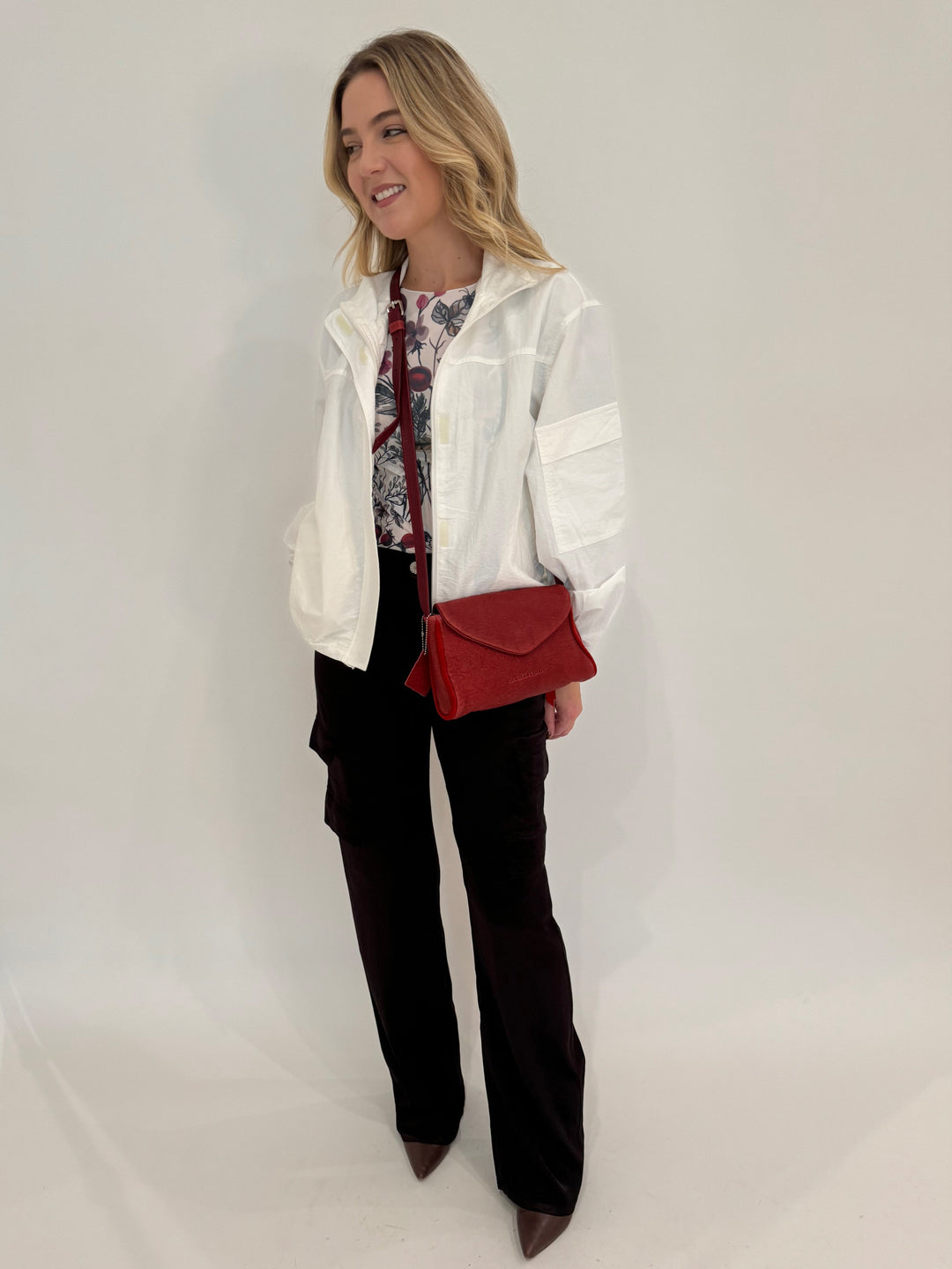 BK Linda Nylon Cropped Windbreaker in Off White with AMB Hello Blossom Second Skin Raw Edge Top underneath, paired with Marrakech Zendaya Silky Cargo Pants in Black, bag Daniella Lehavi Kensington Envelope Crossbody Clutch Bag in Rosso Red - all available at Barbara Katz