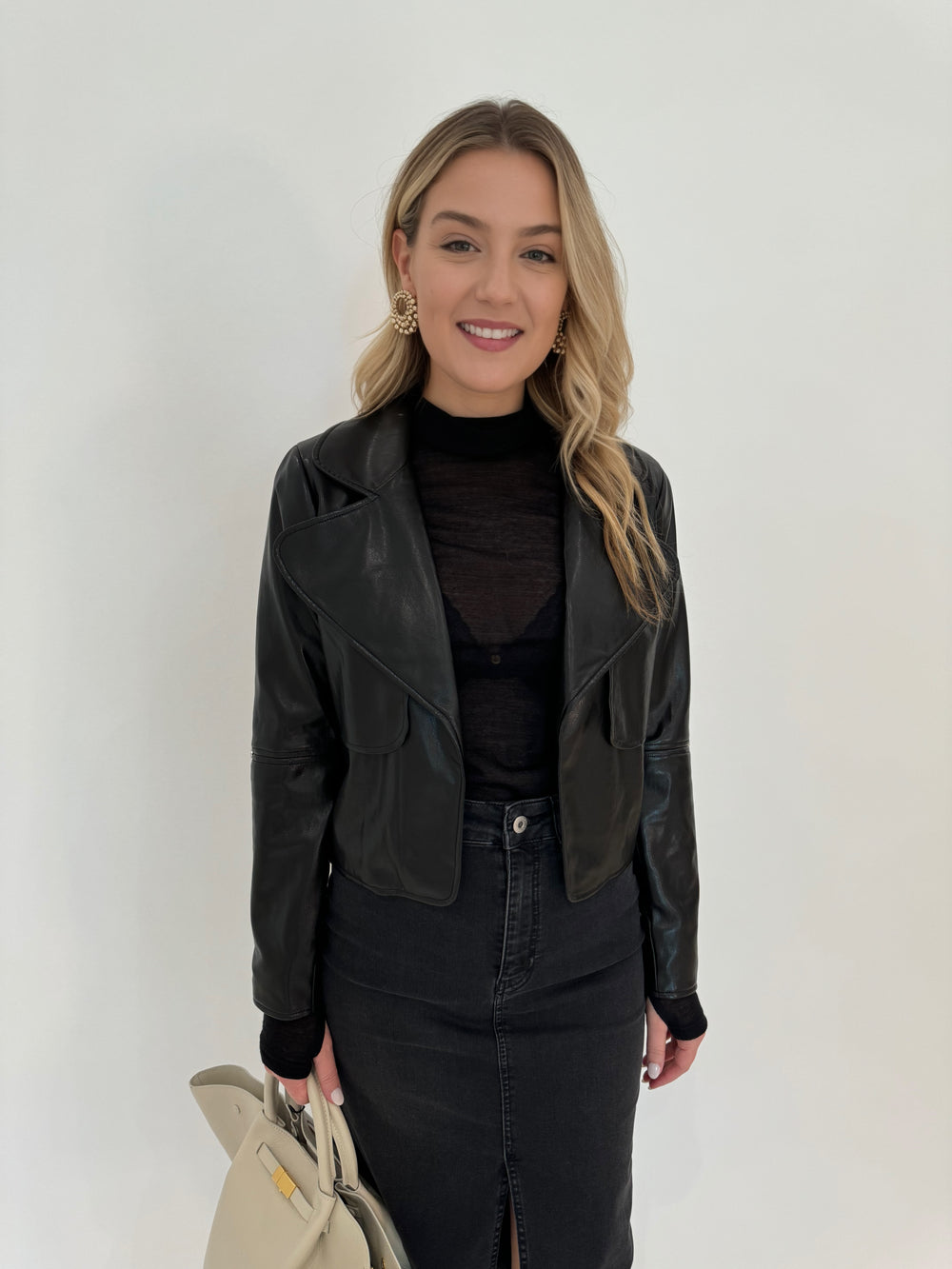 Adroit Atelier Ninon Vegan Leather Jacket in Black with Aldomartins Black Norin Top underneath, paired with Elliott Lauren Geneva Jean Midi Skirt available at Barbara Katz