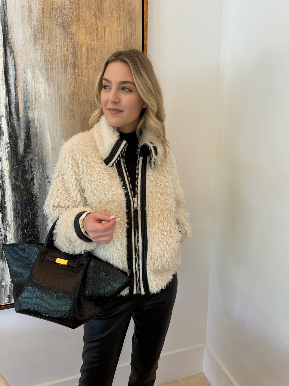 Adroit Atelier Carrie Short Mongolian Faux Fur Coat in Ivory paired with Peace of Cloth Black Faux Leather Slim Jeans, bag DeMellier The New York Tote in Black Croc Effect, all available at Barbara Katz