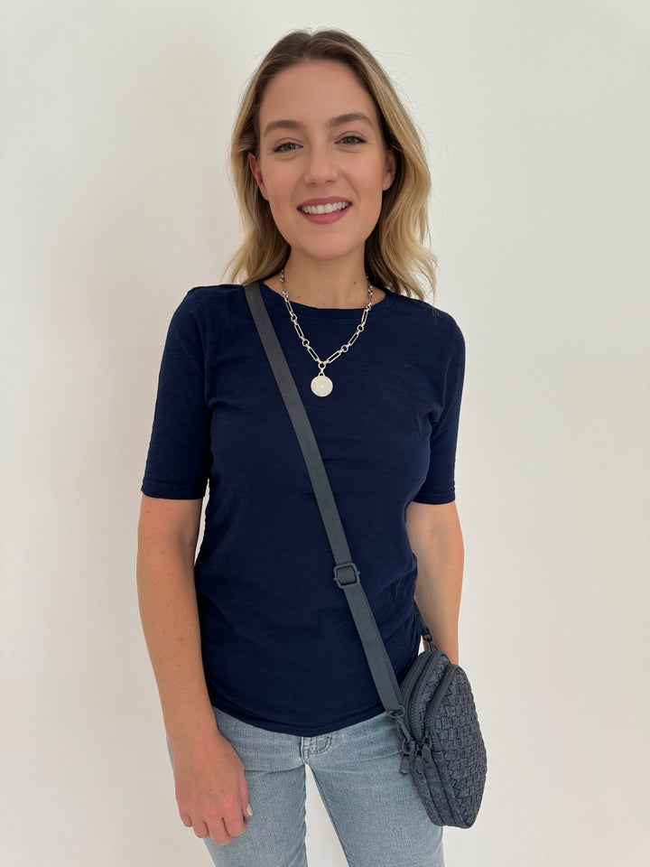 Elliott Lauren Side Ruched Crew Neck Top in Midnight Blue paired with Frame Le Easy Flare Raw Fray Jeans, and bag Sol and Selene Divide & Conquer Woven Crossbody Bag in Dark Denim