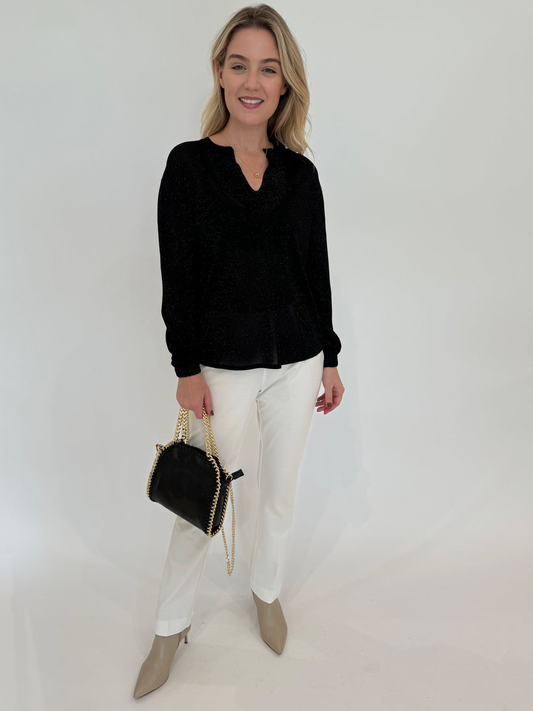 Kinross Cashmere Shimmer Splitneck Long Sleeve Sweater in Black paired with Peace of Cloth Jules Paramount Knit Pants in White and BK Luxe Metallic Leather Bag in Black available at Barbara Katz