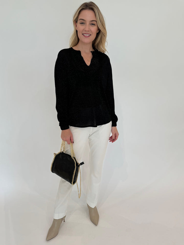 Kinross Cashmere Shimmer Splitneck Long Sleeve Sweater in Black paired with Peace of Cloth Jules Paramount Knit Pants in White and BK Luxe Metallic Leather Bag in Black available at Barbara Katz