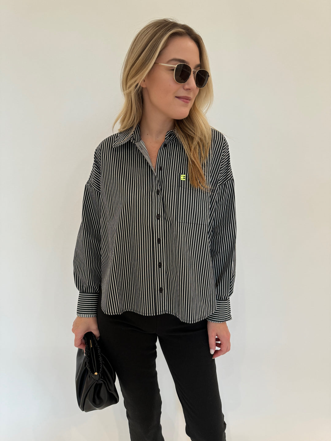 Essentiel Antwerp Glee Striped Shirt in Black Combo paired with Lysse Ankle Denim Bootcut Pants in Black, Le Specs Neptune Deux Sunglasses and DeMellier Miami Clutch in Black - all available at Barbara Katz