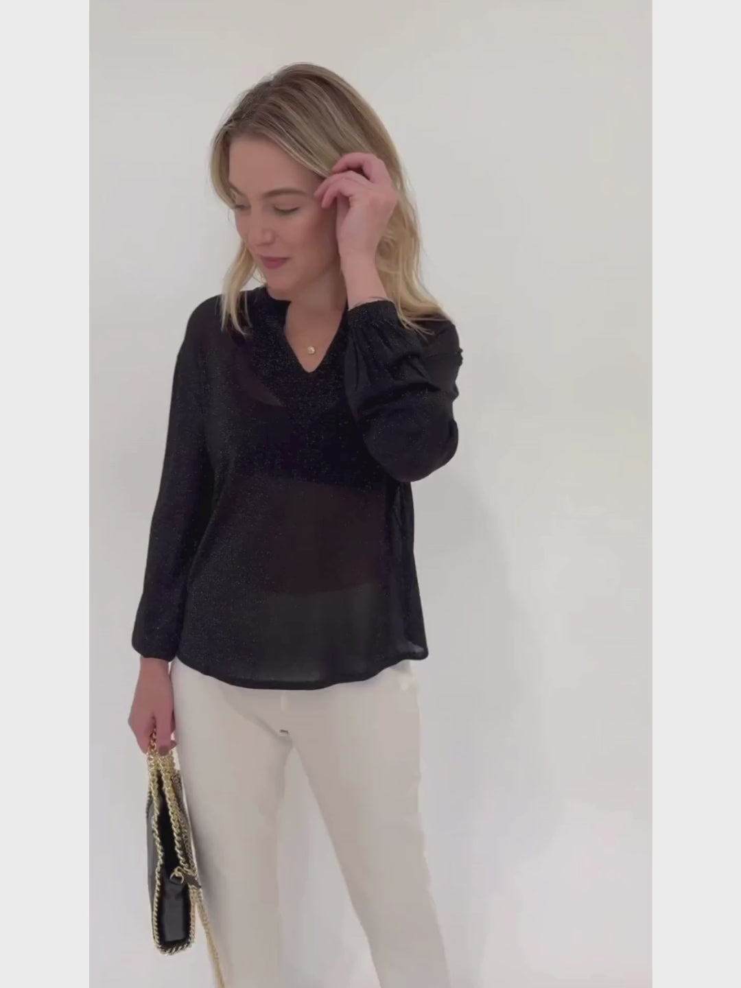 Kinross Cashmere Shimmer Splitneck Long Sleeve Sweater in Black paired with Peace of Cloth White Jules Paramount Knit Pants and BK Black Luxe Metallic Leather Bag available at Barbara Katz