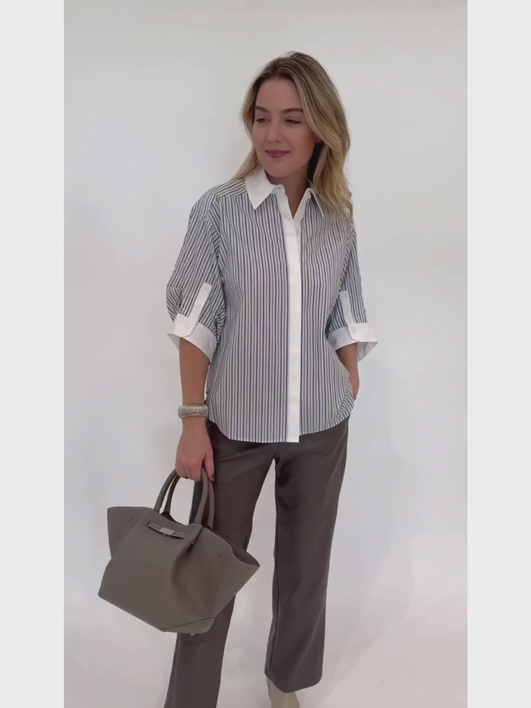 Simkhai Gemma Three-Quarter Sleeve Shirt in Cool Gray Stripe paired with Max Mara Struzzo Vegan Leather Pants in Hazelnut and DeMellier The Midi New York Tote Bag in Stone Gray - all available at Barbara Katz