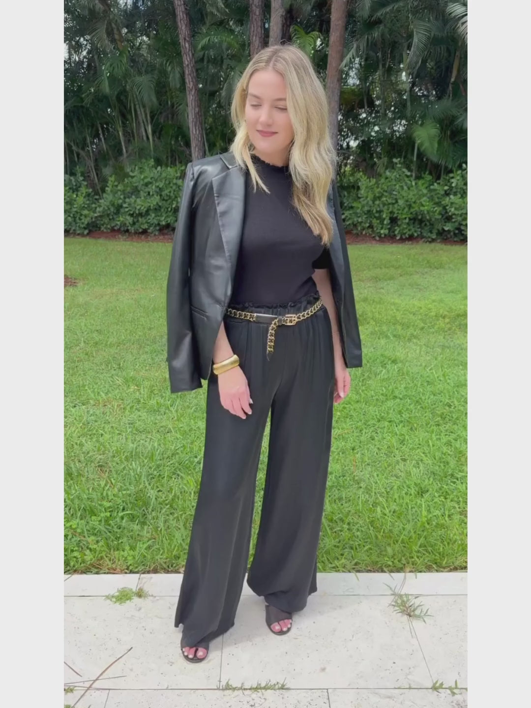 Oui Luna Ruffle Edge Short Sleeve Sweater in Black layered with Adroit Atelier Black Ninon Vegan Leather Jacket, paired with BK Black Italian Silky Palazzo Pants, all available at Barbara Katz